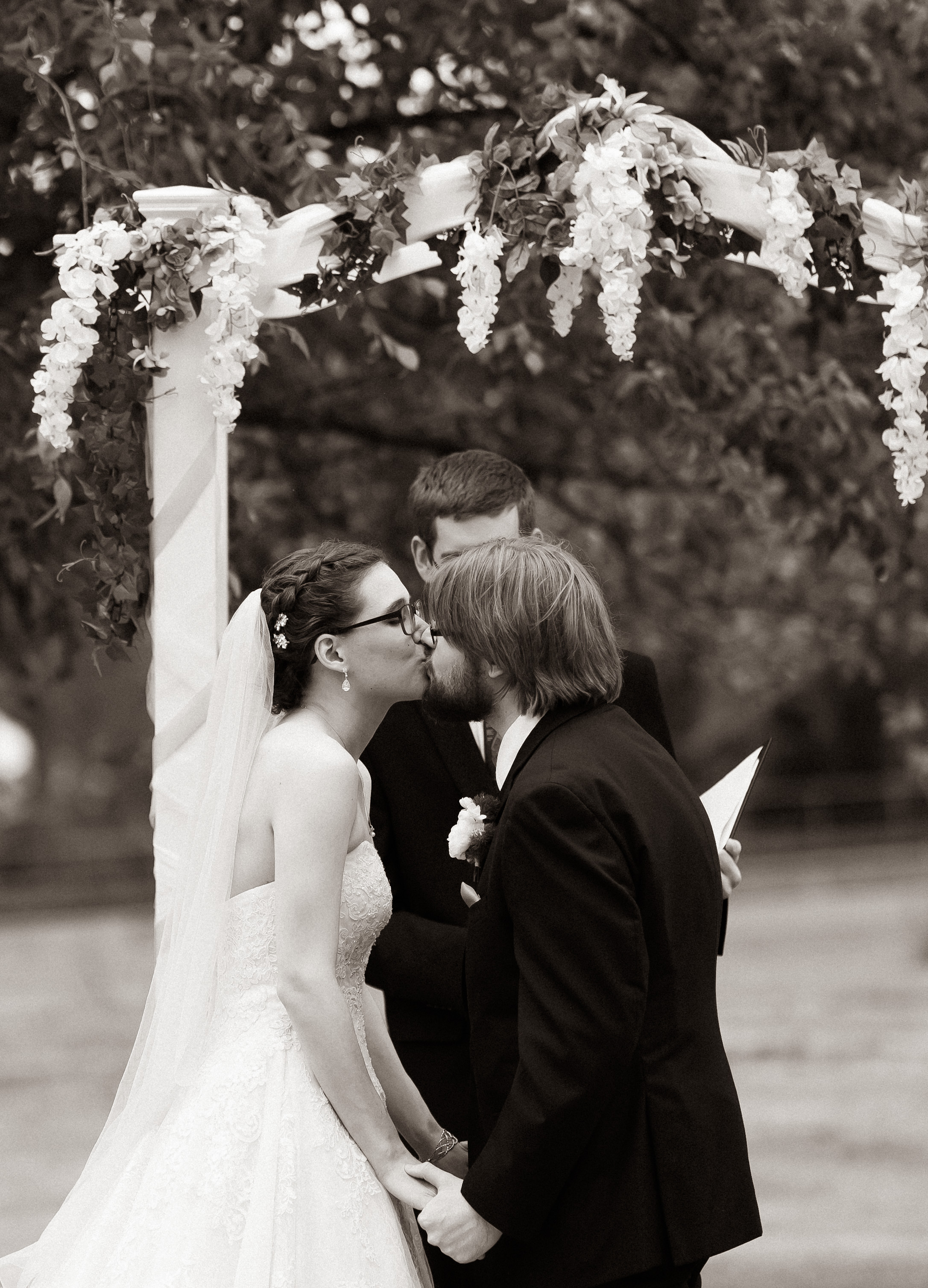 A grayscale photo of the kiss from my wedding.  Gwen is visible on the left, I'm on the right, and our officiant, who you may recognize as Cory from Board Brains, is behind us in the middle.
